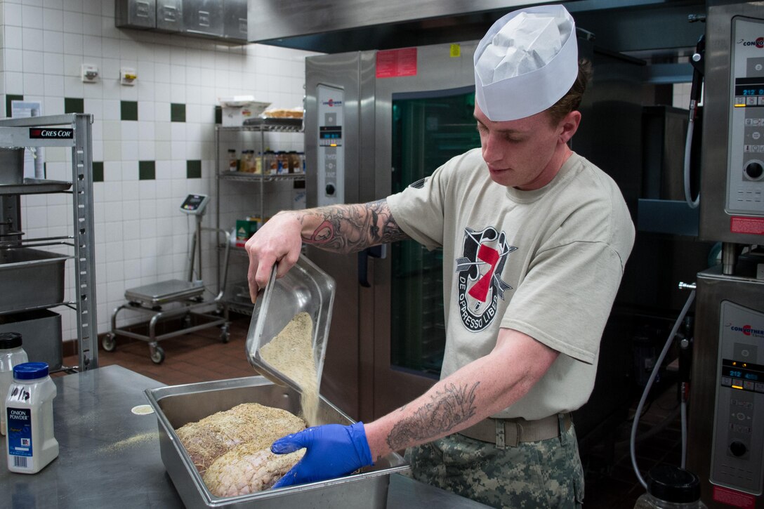 A Green Beret spreads seasoning over ham roasts as he and others prepare a Thanksgiving dinner in the unit’s dining facility on Eglin Air Force Base, Fla., Nov. 23, 2015. The soldier, assigned to the 7th Special Forces Group and other cooks, prepared over 600 lbs. of turkey, 115 lbs. of steamship round and 184 lbs. of ham for serving to the group’s soldiers, families and friends. U.S. Army photo by Maj. Thomas Cieslak