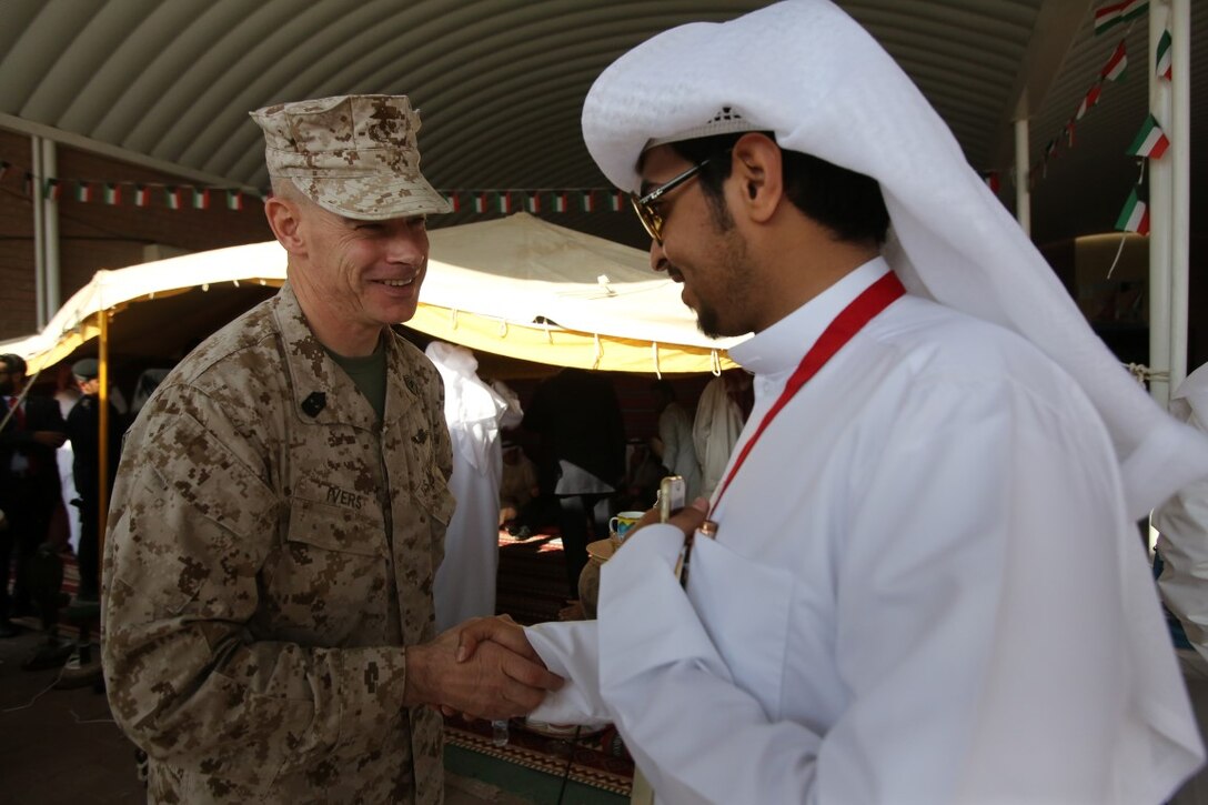 U.S. Marine Master Gunnery Sgt. Brian E. Ivers, a Gulf War veteran currently assigned to Special Purpose Marine Air Ground Task Force—Crisis Response—Central Command, greets a member of the community during a celebration commemorating the 25th anniversary of the liberation of Kuwait at a local middle school in Kuwait City, Nov. 17, 2015. In attendance of the event was Douglas A. Silliman, the U.S. ambassador to Kuwait, along with Kuwaiti dignitaries and members of the U.S. armed forces. The American service members were recognized during the ceremony and had the opportunity to interact with students and local community members. (U.S. Marine Corps Photo by Sgt. Rick Hurtado / Released)