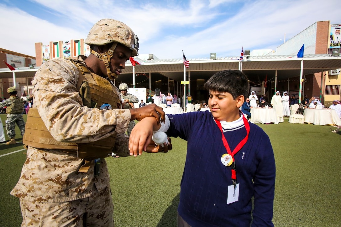 A U.S. Navy corpsman, assigned to Special Purpose Marine Air Ground Task Force—Crisis Response—Central Command, demonstrates basic medical injury treatment procedures during a celebration commemorating the 25th anniversary of the liberation of Kuwait at a local middle school in Kuwait City, Nov. 17, 2015. In attendance of the event was Douglas A. Silliman, the U.S. ambassador to Kuwait, along with Kuwaiti dignitaries and members of the U.S. armed forces. The American service members were recognized during the ceremony and had the opportunity to interact with students and local community members. 