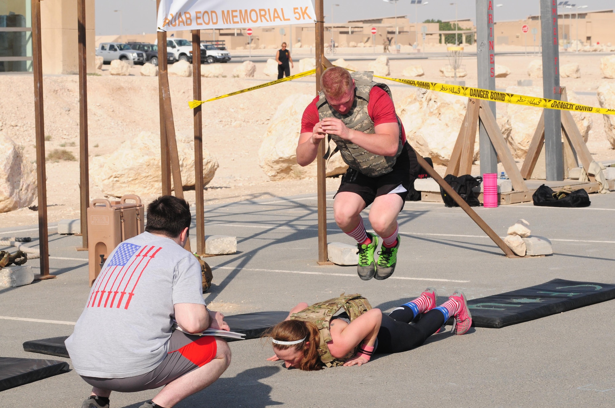 Military members worked hard to complete sets of burpees at Al Udeid Air Force Base Nov. 21. After each couplet there were 16 lateral partner over burpees. The number 16 represents 16 point hits which are automatic failures for EOD technicians in school. (U.S Air Force photo courtesy of Senior Master Sgt. Stephan Kovacs)