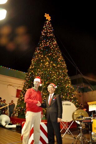 Col. Christopher A. Feyedelem, left, shakes hands with Urasoe City Mayor Tetsuji Matsumoto during the Camp Kinser Christmas Tree Lighting Ceremony Nov. 27 aboard Camp Kinser, Okinawa, Japan. Hundreds of participants from all units on Kinser and children from various organizations such as Boy Scouts and Girl Scouts of America participated in the event. Feyedelem is the commanding officer of Headquarters Regiment, 3rd Marine Logistics Group, III Marine Expeditionary Force. (Courtesy Photo by Toshi Nakamoto) 