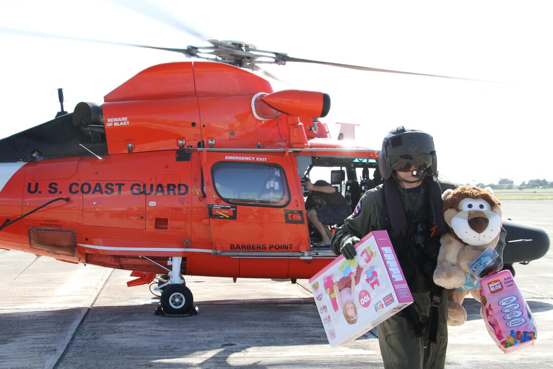 Coast Guard Petty Officer 1st Class Daryk Brekke unloads toys from an MH-65 Dolphin helicopter at Kalaeloa Airport on Oahu, Hawaii, Nov. 29, 2015. As part of the Toys for Tots program, Coast Guardsmen from Air Station Barbers Point, Hawaii, collected toys and donations to give to Marines for delivery to disadvantaged children for Christmas. U.S. Coast Guard photo by Petty Officer 2nd Class Tara Molle