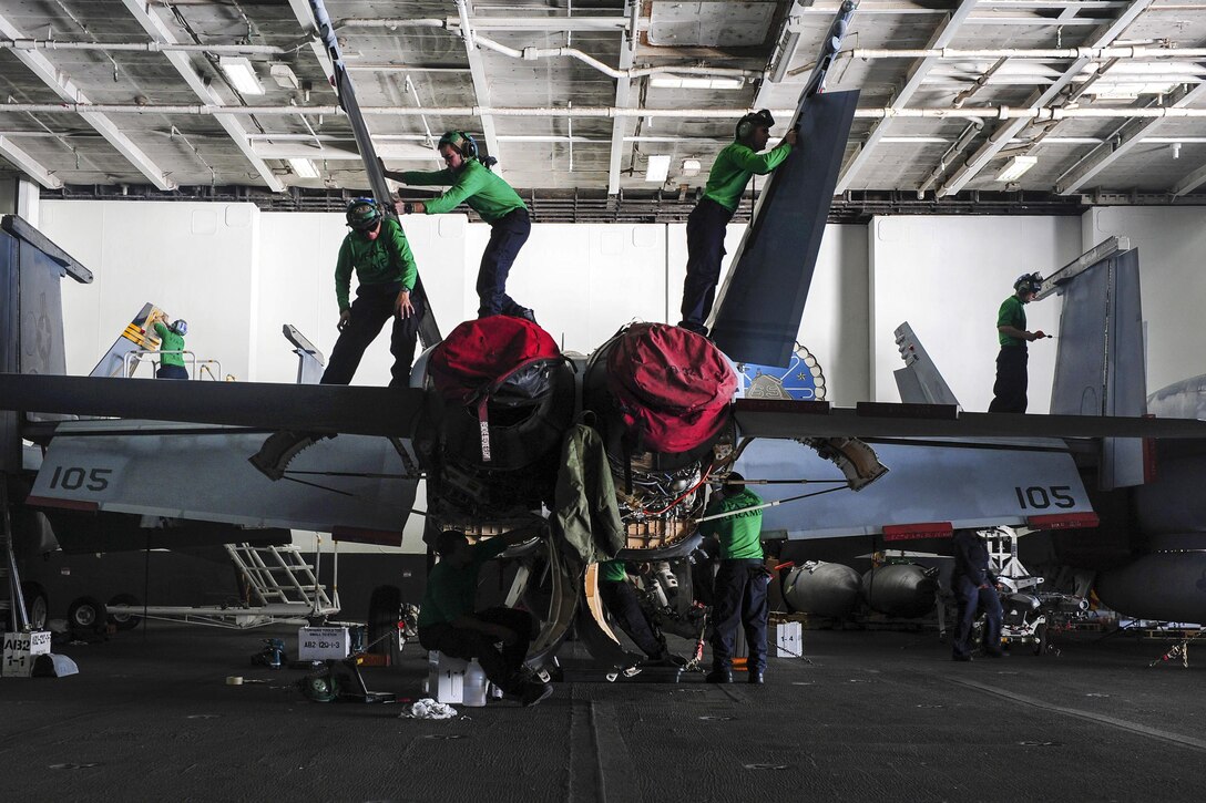 U.S. sailors perform maintenance on an F/A-18F Super Hornet in the hangar bay of the aircraft carrier USS Dwight D. Eisenhower in the Atlantic Ocean, Nov. 28, 2015. The sailors are assigned to Strike Fighter Squadron 32. U.S. Navy photo by Petty Officer 3rd Class Taylor L. Jackson