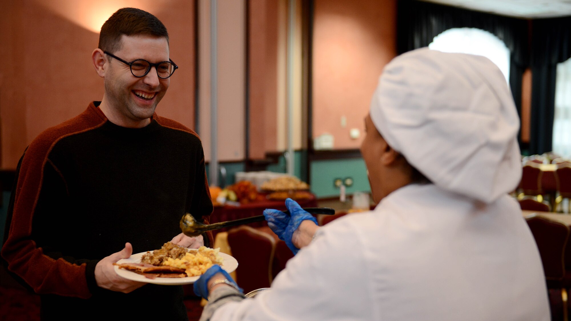 U.S. Air Force Capt. Steven Schwerdtfeger, 31st Medical Support Squadron TRICARE flight commander, gets a serving of gravy from Senior Master Sgt. Karla Jeremiah-Griffith, 31st Dental Squadron senior enlisted leader, Nov. 26, 2015, at Aviano Air Base, Italy. Wing leaders served La Dolce Vita dining facility and La Bella Vista Club customers on Thanksgiving Day. (U.S. Air Force photo by Staff Sgt. R.J. Biermann/Released)