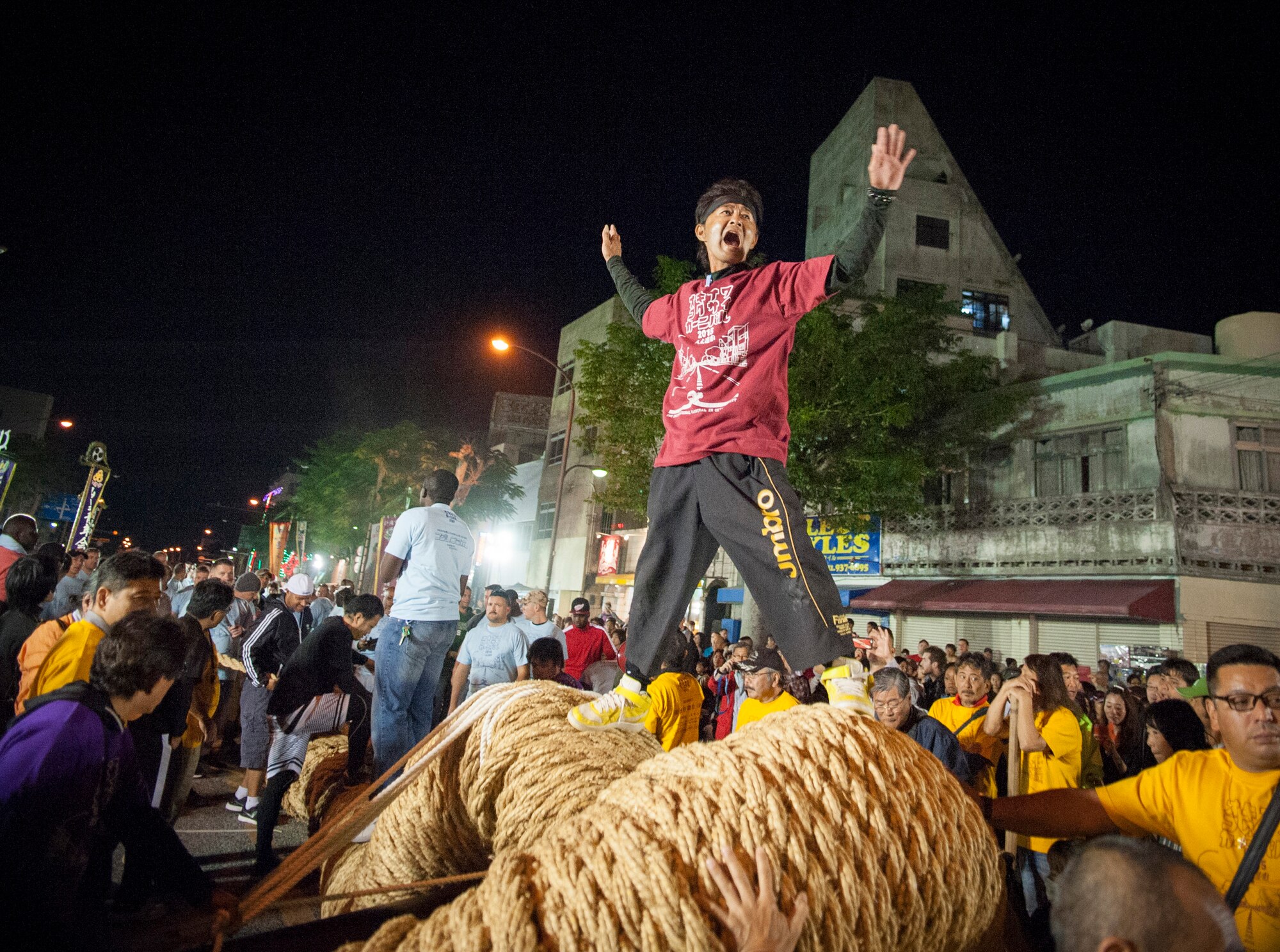 A local participant motivates the crowd as the two giant ropes are joined together for the traditional tug-of-war contest, Nov. 28, 2015, at the Okinawa International Carnival. The tug-of-war represents the joining together of East and West through friendly competition. (U.S. Air Force photo by Master Sgt. Jason W. Edwards)