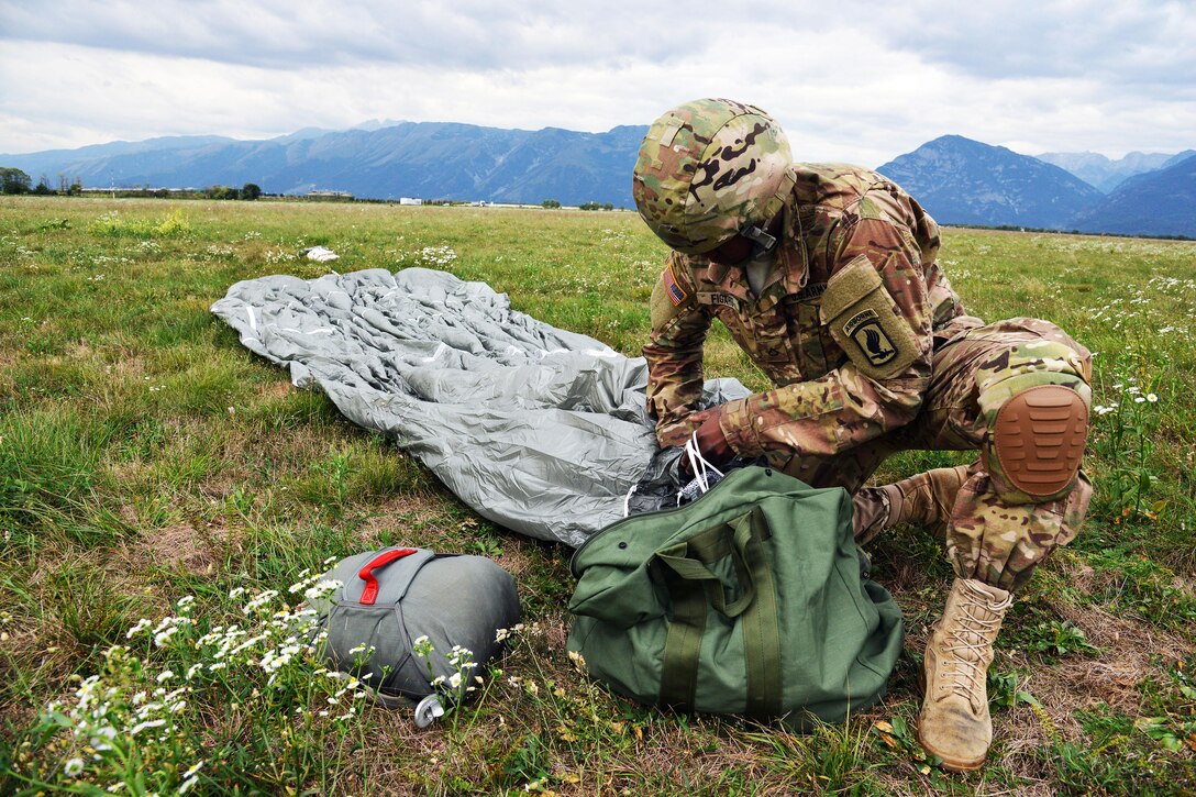 A U.S. Army paratrooper recovers gear after a jump from a Chinook helicopter at Juliet drop zone in Pordenone, Italy, Sept. 30, 2015. U.S. Army photo by Paolo Bovo