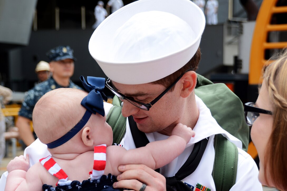 U.S. Navy Petty Officer 3rd Class Stephen Ligget holds his new baby after the arrival of the USS Ronald Reagan at Commander Fleet Activities Yokosuka, Japan, Oct. 1, 2015. The ship replaces the USS George Washington  as America’s only forward-deployed aircraft carrier. Ligget is an electrician's mate. U.S. Navy photo by Petty Officer 2nd Class Peter Burghart