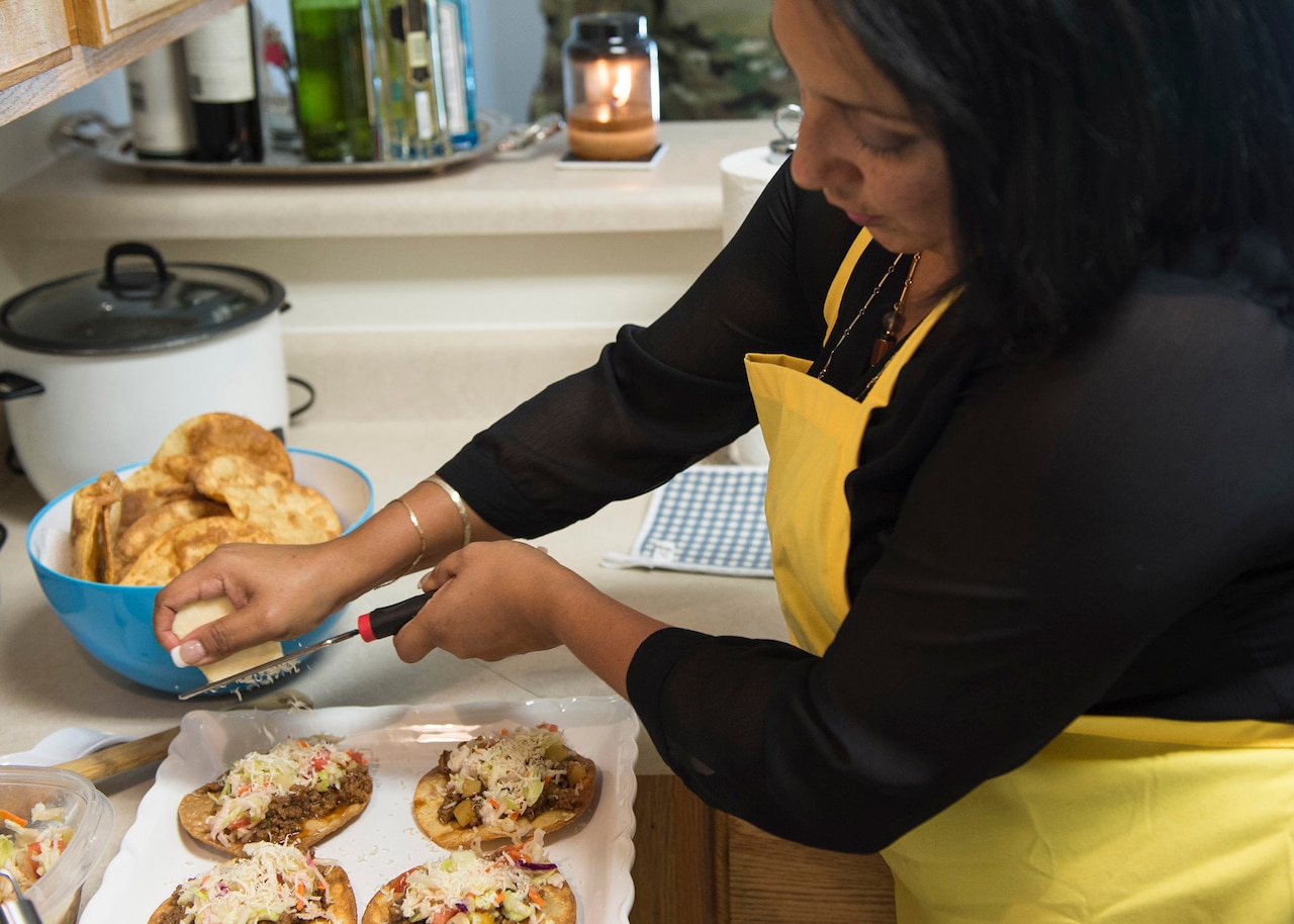 Jenny Lopez-Guerrero, wife of Army Capt. Daniel Lopez-Guerrero, grates cheese onto patelitos at Fort Lee, Va., Sept. 11, 2015.