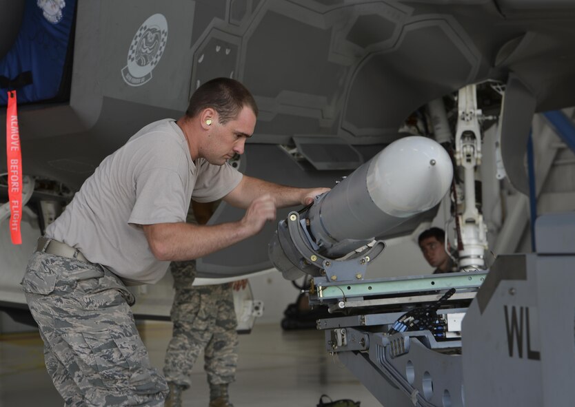 Staff Sgt. Matthew Schlotthauer, 33rd Aircraft Maintenance Squadron weapons load team chief, transfers a missile into an F-35A Lightning II during a weapons load competition at Eglin Air Force Base, Fla., Sept. 30, 2015. The F-35A Lightning II carries an internal payload to maximize its stealth capability while deployed. (U.S. Air Force Photo/Senior Airman Andrea Posey)