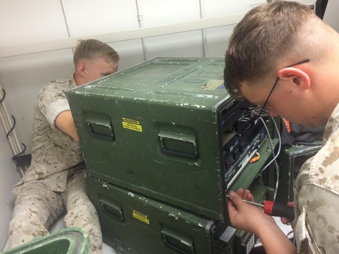LCpl Tucker assists LCpl Goodfellow installing a Multiplexer Modem in the AN/MRC-142C.