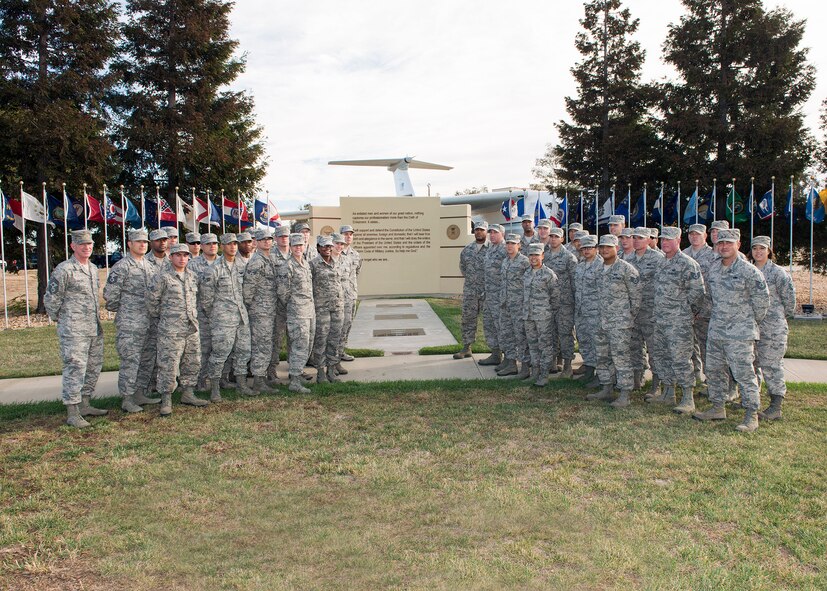 Chief Master Sgt. Alan G. Boling, 60th Air Mobility Wing command chief, far left, poses for a photo with students of the Sgt. Paul P. Ramoneda Airman Leadership School class 15-G in front of the Oath of Enlistment Wall. ALS class 15-G, with the help of Airmen from the 60th Maintenance Squadron and 60th Civil Engineer Squadron, gave the wall a much needed face lift over the past six months. The group of 38 Airmen helped refurbish the wall, which was originally built in 1999. The wall reflects the Oath of Enlistment inscribed on it which reminds readers each time we take that oath, to remember what being a member of the Armed Forces all is about.  It represents our purpose, and it's very fitting that it's surrounded by all the state flags, representing our diverse force and introduction to the Profession of Arms. The enlisted stripes that run down the center of the monument are set in granite and symbolize the strength of our enlisted force. (U.S. Air Force photo/T.C. Perkins)