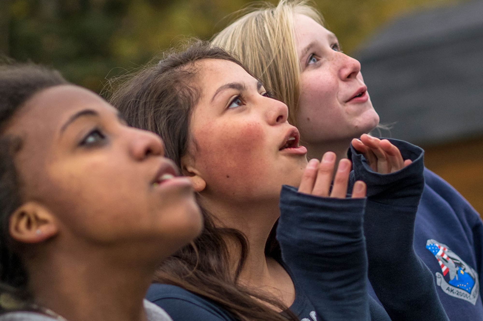 Aszia Fisher, Meadow Burley, and Abi Odom, students from the Eagle River High School JROTC program, cheer for a fellow cadet as he competes in an obstacle course during the firefighting demo challenge on JBER Sept. 25.