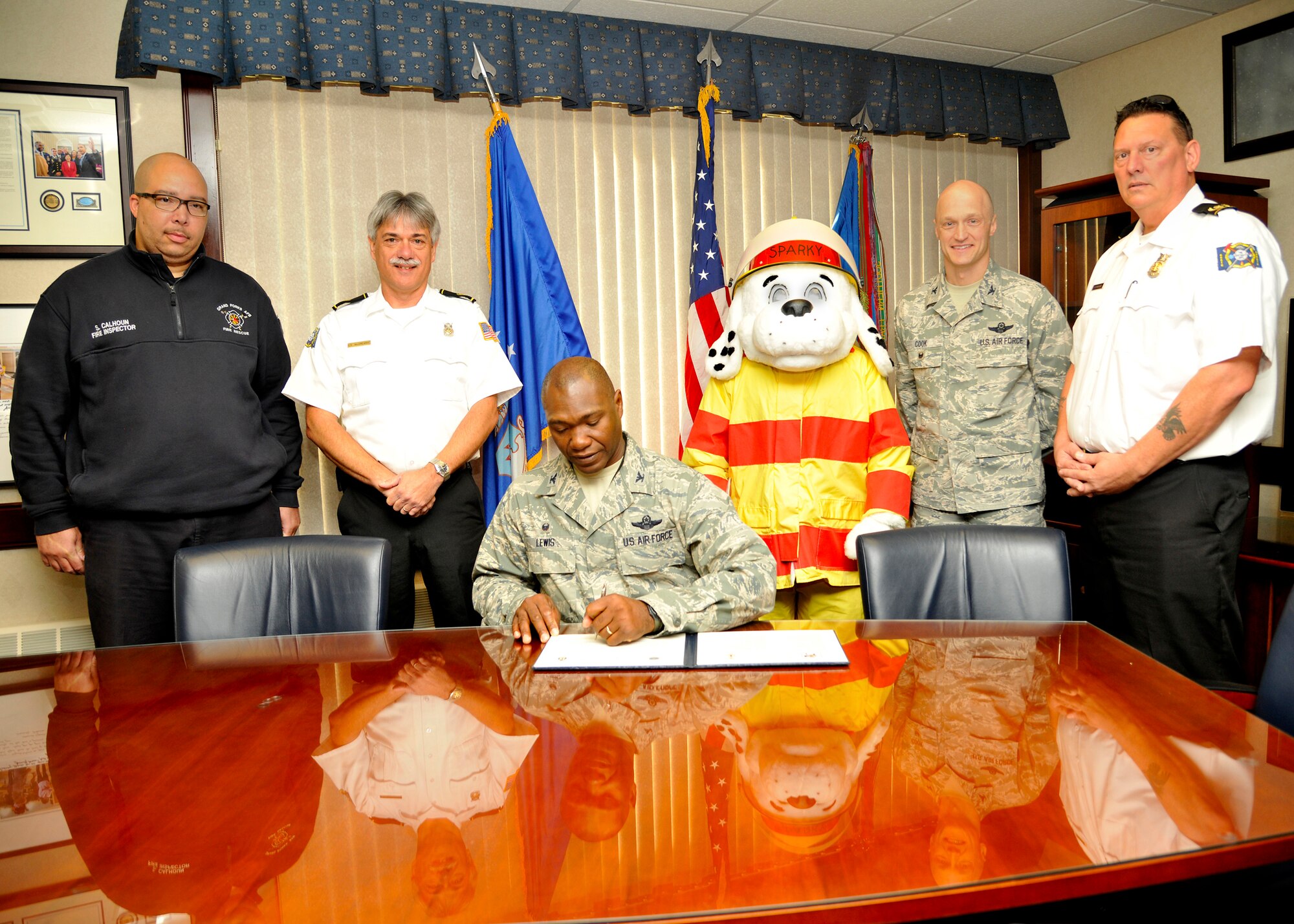 Col. Rodney Lewis, 319th Air Base Wing commander, signs the 2015 Fire Prevention Week proclamation, accompanied by Col. Robert Cook, 319th ABW vice commander, and members of the 319th Civil Engineer Squadron Fire Department Oct. 1, 2015 at the wing headquarters building on Grand Forks Air Force Base, North Dakota.  The signing of the proclamation officially kicked off the base’s Fire Prevention Week events that will run from Oct. 4 -10 and is coordinated by the Grand Forks Air Force Base Fire Department. (U.S. Air Force photo by Senior Airman Xavier Navarro/Released)