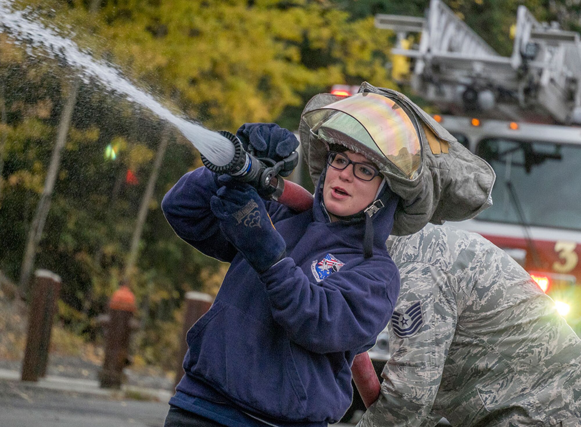 Danny Thomas, a junior in the Eagle River High School JROTC program, uses a fire hose during a visit with Airmen assigned to the 673d Civil Engineer Squadron on Joint Base Elmendorf-Richardson Sept. 25. The students ran through buddy-team drills with firefighting equipment used by the Airmen for training, and firefighters talked with them about their duties and the rigors of emergency service responders. (U.S. Air Force photo/Justin Connaher)