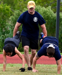 U.S. Air Force Airmen perform a three person wheel barrel exercise during the Air Force Team Cohesion Challenge at Langley Air Force Base, Va., Sept. 25, 2015. The TCC promoted teamwork and leadership skills during a five-hour event. (U.S. Air Force photo by Airman 1st Class Derek Seifert/ Released)