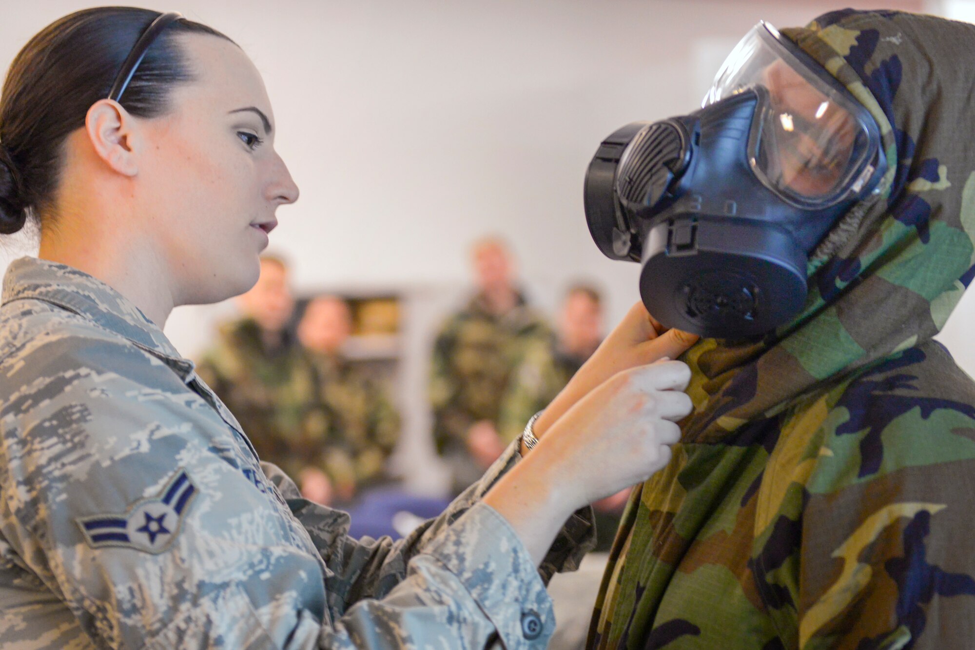 Airman 1st Class Chelsea Asteriadis, 374th Civil Engineer Squadron emergency management apprentice, shows Airmen how to properly don their chemical gear during a Chemical, Biological, Radiological, Nuclear and Explosives defense survival skills refresher course at Yokota Air Base, Japan, Sept. 29, 2015. Part of Asteriadis’ job is to teach Airmen how to keep themselves safe by donning gear correctly and preventing leaks. (U.S. Air Force Photo by Airman 1st Class Elizabeth Baker/Released)