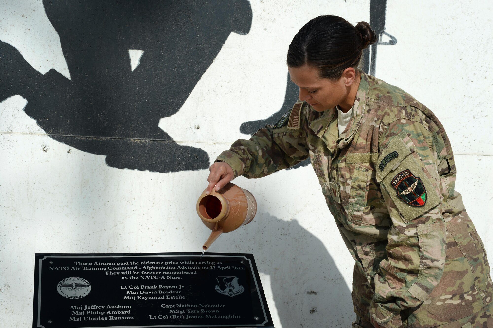 U.S. Air Force Tech. Sgt. Valarie, Train, Advise, Assist Command – Air (TAAC-Air), clean off the plaque at the NATO Air Training Command – Afghanistan (NATC-A) Nine Memorial Forward Operating Base Oqab, Afghanistan, Sept. 22, 2015. The 438th Air Expeditionary Advisor Group with funds and donations by the Enlisted Coalition Council built the NATC-A Nine Memorial in April 2013. (U.S. Air Force photo by Staff Sgt. Sandra Welch/released)