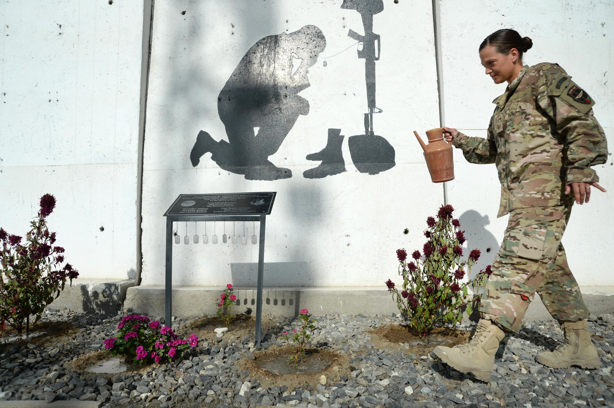 U.S. Air Force Tech. Sgt. Valarie, Train, Advise, Assist Command – Air (TAAC-Air), waters the flowers around the NATO Air Training Command – Afghanistan (NATC-A) Nine Memorial Forward Operating Base Oqab, Afghanistan, Sept. 22, 2015. The 438th Air Expeditionary Advisor Group with funds and donations by the Enlisted Coalition Council built the NATC-A Nine Memorial in April 2013. (U.S. Air Force photo by Staff Sgt. Sandra Welch/released)