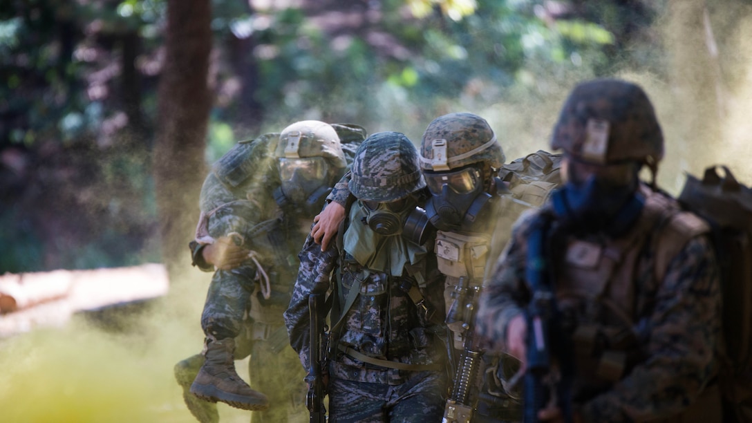 Republic of Korea Marine Lance Cpl. Jun Shin, center, supports a U.S. Marine moving to safety during a gas attack drill as part of Korean Marine Exchange Program 15-12 at Gunha-Rhi, Republic of Korea, Sept. 17, 2015. The drill was part of KMEP 15-12, an exercise that enhances the ROK and U.S. alliance, promotes stability on the Korean Peninsula and strengthens ROK and U.S. military capabilities and interoperability. Shin is with 2nd Company, 11th Battalion, 1st Regiment, 2nd Marine Division, ROK Headquarters Marine Corps.