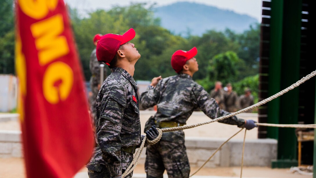 Republic of Korea Marine ranger instructors act as belay men during a company competition among integrated teams of ROK and U.S. Marines during Korean Marine Exchange Program at Yooghuk Dae, Munseu San Mountain, Republic of Korea, Sept. 11, 2015. The U.S. and ROK Marines competed for the fastest company in rappelling, rock climbing and rope climbing before a sprint to the finish line. KMEP 15-12 is a bilateral training exercise that enhances the ROK and U.S. alliance, promotes stability on the Korean Peninsula and strengthens ROK and U.S. military capabilities and interoperability. The ROK Marines are with 11th Battalion, 1st Regiment, 2nd Marine Division, ROK Headquarters Marine Corps.
