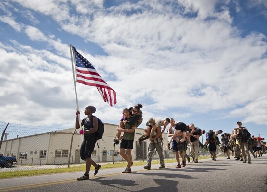 Participants march past the vehicle maintenance facility carrying simulated wounded personnel Sept. 24, 2015, at the GoRuck team building challenge at Eglin Air Force Base, Fla. More than 45 participants pushed themselves through the physical scenarios led by a special forces veteran, to earn the blue and black “GoRuck” patch. (U.S. Air Force photo/Samuel King Jr.)