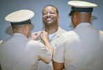 Chief Hospital Corpsman Damien Bush (center) receives his anchors during a pinning ceremony at Joint Base San Antonio-Fort Sam  Houston. Navy Medicine Training Support Center and Navy Operational Support Center San Antonio came together to pin 24 chiefs following a six-week indoctrination phase.