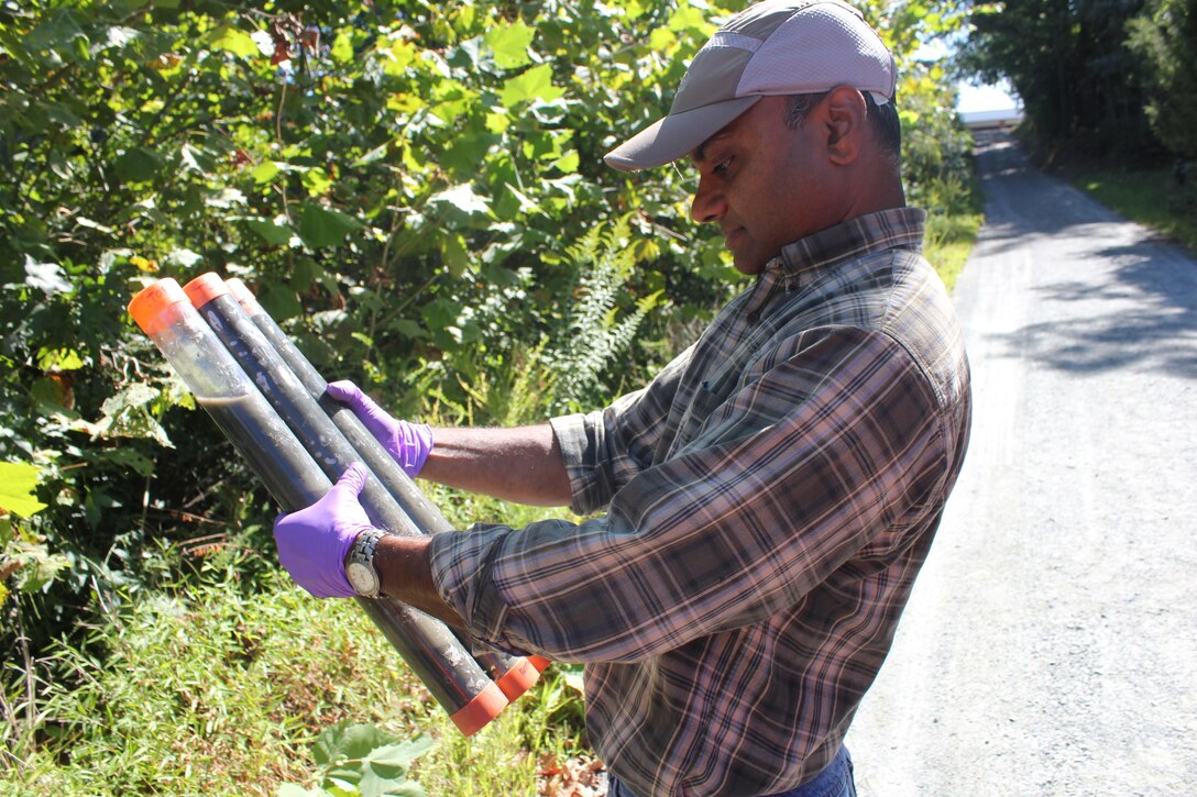 Dr. Upal Ghosh examines core samples taken from Abraham’s Creek on Sept. 15. At a previous visit to the site, Ghosh and his team treated one plot of the creek with activated carbon and one plot with a combination of carbon and anaerobic and aerobic microorganisms. In lab studies, the carbon and microorganisms were shown to work effectively together to block the availability of PCBs to the food chain.