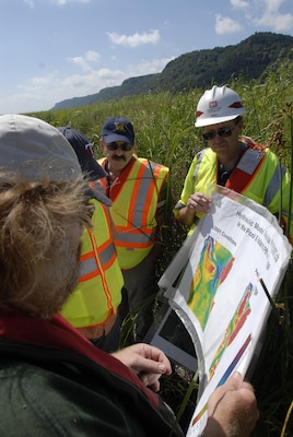 Members of the Wisconsin Department of Natural Resources and the U.S. Army Corps of Engineers look at aerial maps of the Mississippi River while conducting a tour to see the island creation process in action.