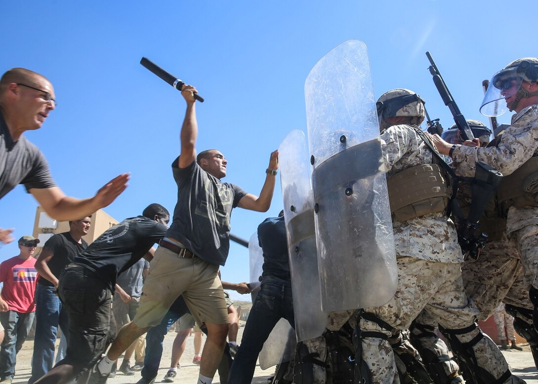 Marines in a riot control formation with 1st Law Enforcement Battalion, I Marine Expeditionary Force Headquarters Group; 1st Battalion, 5th Marine Regiment and 2nd Battalion, 11th Marine Regiment, 1st Marine Division, defend themselves against protestors in a simulated mob aboard Marine Corps Base Camp Pendleton, Calif., Sept. 25, 2015. The course was conducted as part of an annual training event meant to educate Marines in the de-escalation of situations, while showing appropriate escalation of force in response to riots. (U.S. Marine Corps photo by Pfc. Devan K. Gowans/Released)