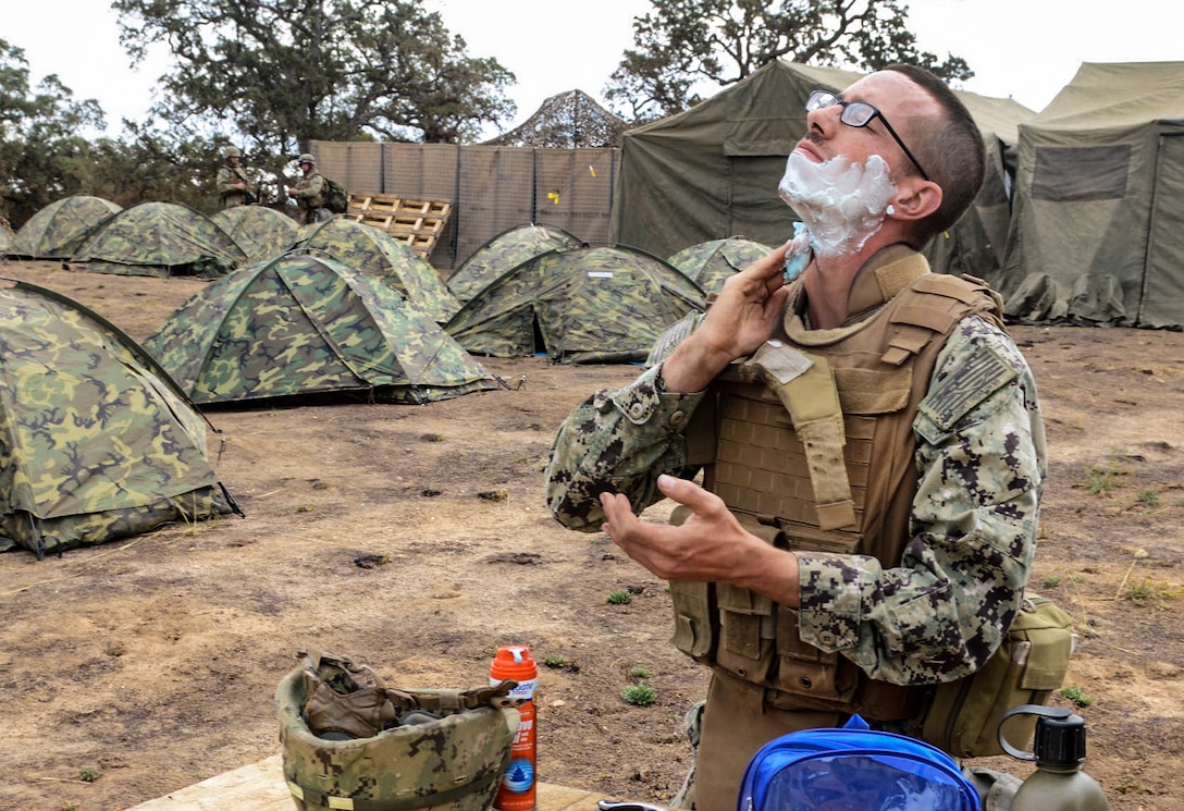 Navy Petty Officer 3rd Class Michael Whisenhunt shaves during a field training exercise on Fort Hunter Liggett, Calif., Sept. 28, 2015. Whisenhunt, a construction electrician, is assigned to Naval Mobile Construction Battalion 4. The exercise tests the battalion's ability to enter hostile locations, build assigned construction projects and defend against enemy attacks, using realistic scenarios. U.S. Navy photo by Petty Officer 1st Class Rosalie Chang