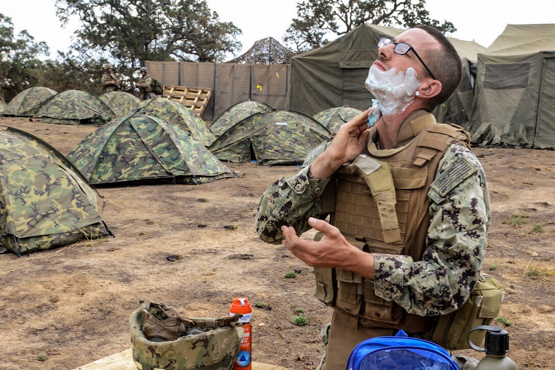 Navy Petty Officer 3rd Class Michael Whisenhunt shaves during a field training exercise on Fort Hunter Liggett, Calif., Sept. 28, 2015. Whisenhunt, a construction electrician, is assigned to Naval Mobile Construction Battalion 4. The exercise tests the battalion's ability to enter hostile locations, build assigned construction projects and defend against enemy attacks, using realistic scenarios. U.S. Navy photo by Petty Officer 1st Class Rosalie Chang
