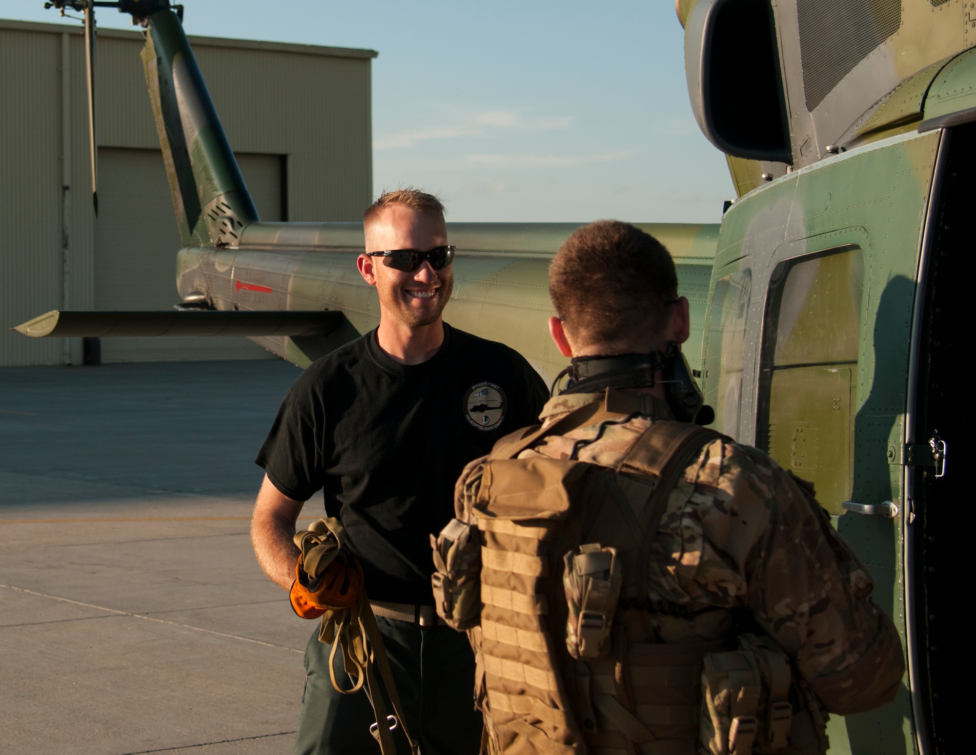Ben Postma, M1 Support Services aircraft mechanic, talks with a 790th Missile Security Forces Squadron Tactical Response Force Airman on F.E. Warren Air Force Base, Wyo., June 12, 2015. The defender just returned from the 90th Missile Wing Missile Complex on the UH-1N “Huey” Bell Helicopter that Postma was preparing to inspect. (U.S. Air Force photo by Senior Airman Jason Wiese)