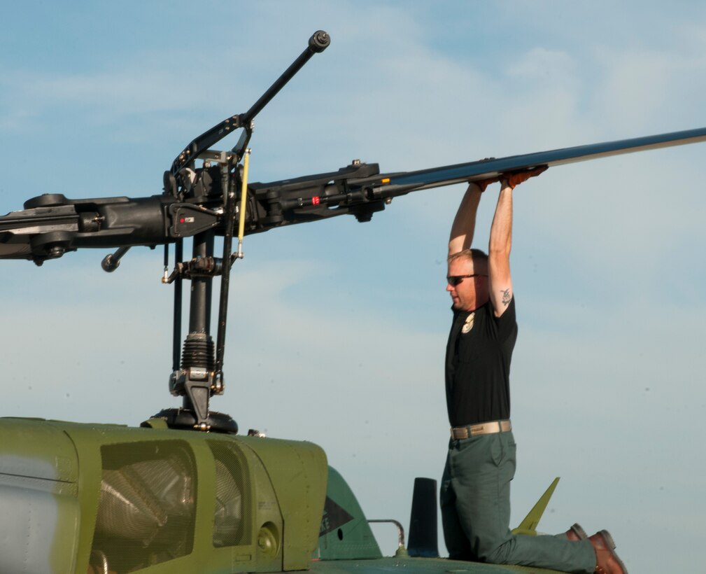 Ben Postma, M1 Support Services aircraft mechanic, lifts a propeller blade of a UH-1N “Huey” Bell Helicopter on F.E. Warren Air Force Base, Wyo., June 12, 2015. Lifting one blade lowers the other so it can be reached from the ground and tied to the body of the helicopter, preventing it from spinning freely during maintenance. (U.S. Air Force photo by Senior Airman Jason Wiese)