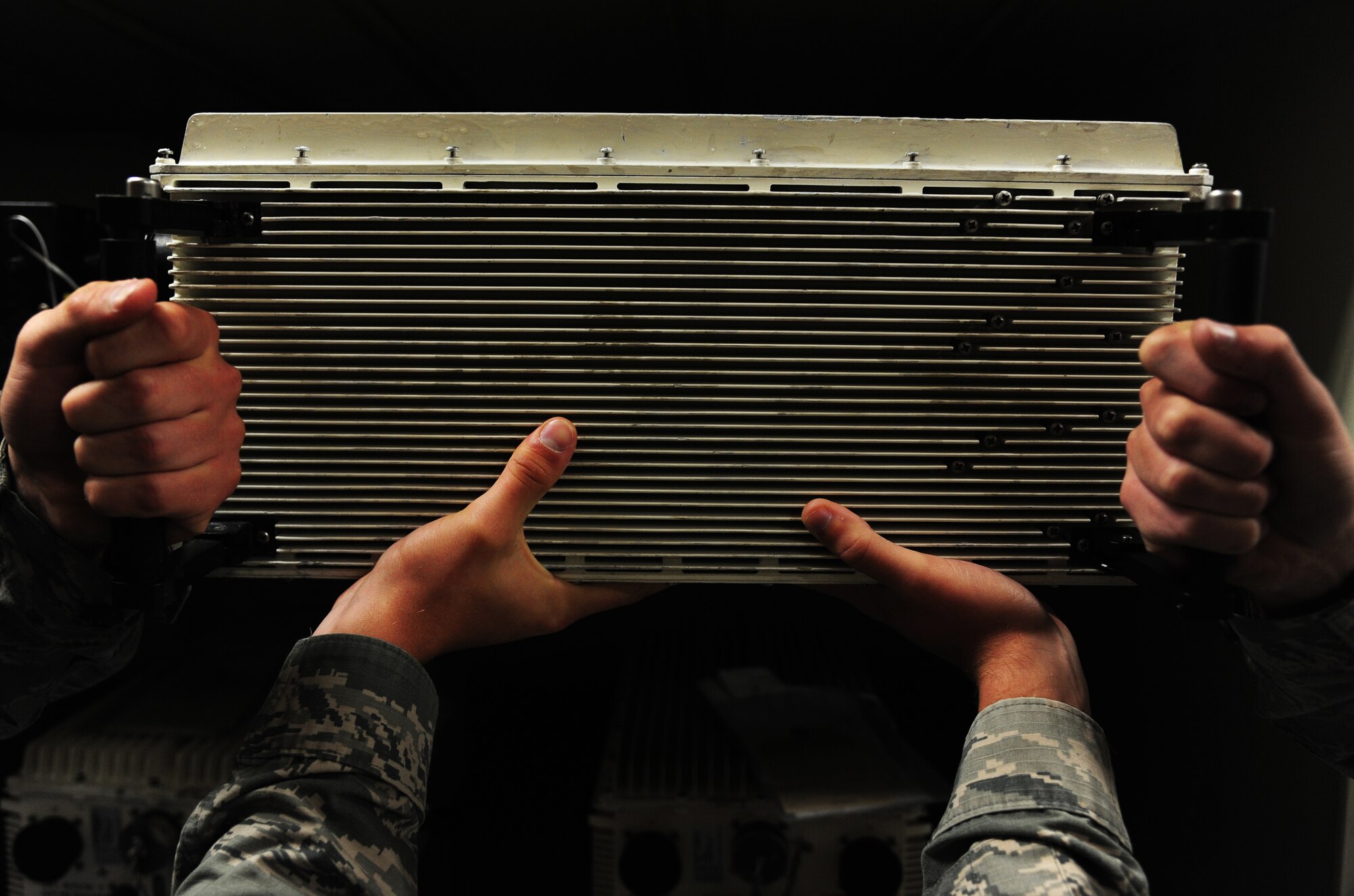 Airman 1st Class Michael Bentley and Bruno Gomes, both, 509th Maintenance Squadron avionics technicians, pick up an actuator remote terminal at Whiteman Air Force Base, Mo., Oct. 1, 2015. The ART helps stimulate B-2 flight controls during operations. (U.S Air Force photos by Senior Airman Keenan Berry/Released)