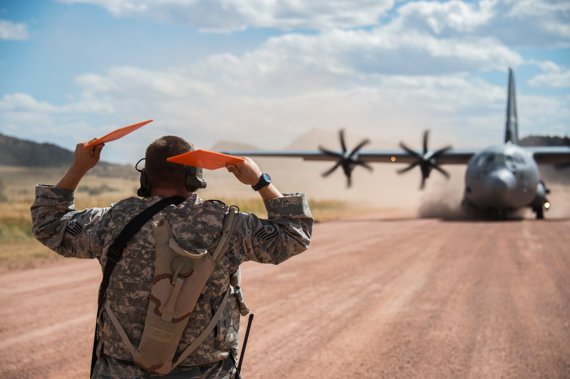Tech Sgt. Ryan Padgett, a ramp coordinator for the 821st Contingency response Squadron from Travis Air Force Base, Calif., marshals in a C-130 Aircraft into parking area at Red Devil Landing Zone, Colo., on September 14, 2015. Approximately 150 Airmen from the 821st Contingency Response Group at Travis Air Force Base, Calif., participated in a first-of-its-kind Joint contingency response exercise from Sept. 8-19 at five locations (Southern California Logistics Airfield, Calif., Freedom Landing Zone, Calif., Gunnison Region Airfield, Colo., Red Devil Landing Zone, Colo., Peterson Air Force Base, Colo., and Fort Carson, Colo.). During the training, 821st CRG Airmen supported more than 275 Soldiers from Fort Carson, Colo., during air drop missions, helicopter training, coordinated Apache air support, and personnel and equipment airlift training. The Contingency Response (CR) training was constructed to primarily develop unique CR-oriented training objectives to improve down range effectiveness in preparation for real-world responses. (U.S. Air Force Photos by Tech. Sgt. Matthew Hannen)