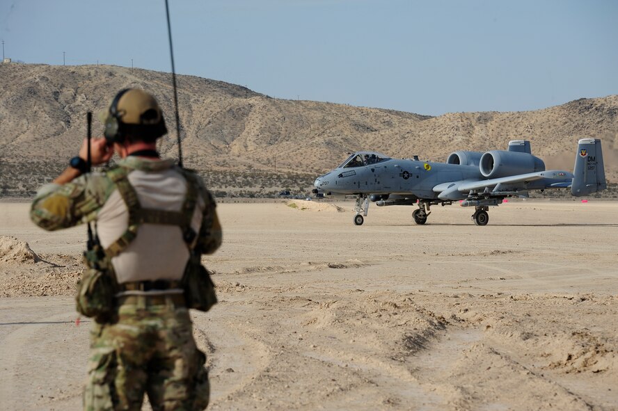 U.S. Air Force combat controller from the 22nd Special Tactics Squadron communicates with a 357th Fighter Squadron A-10C Thunderbolt II pilot taxiing to a parking spot after landing on Bicycle Lake Army Airfield at the National Training Center range, Fort Irwin, Calif., Sept. 22, 2015. The pilots participated in austere landing training during Green Flag-West 15-10. Combat controller’s survey and establish airfields in austere or hostile areas while also providing air traffic control to land aircraft during combat and humanitarian missions. (U.S. Air Force photo by Senior Airman Betty R. Chevalier/Released)