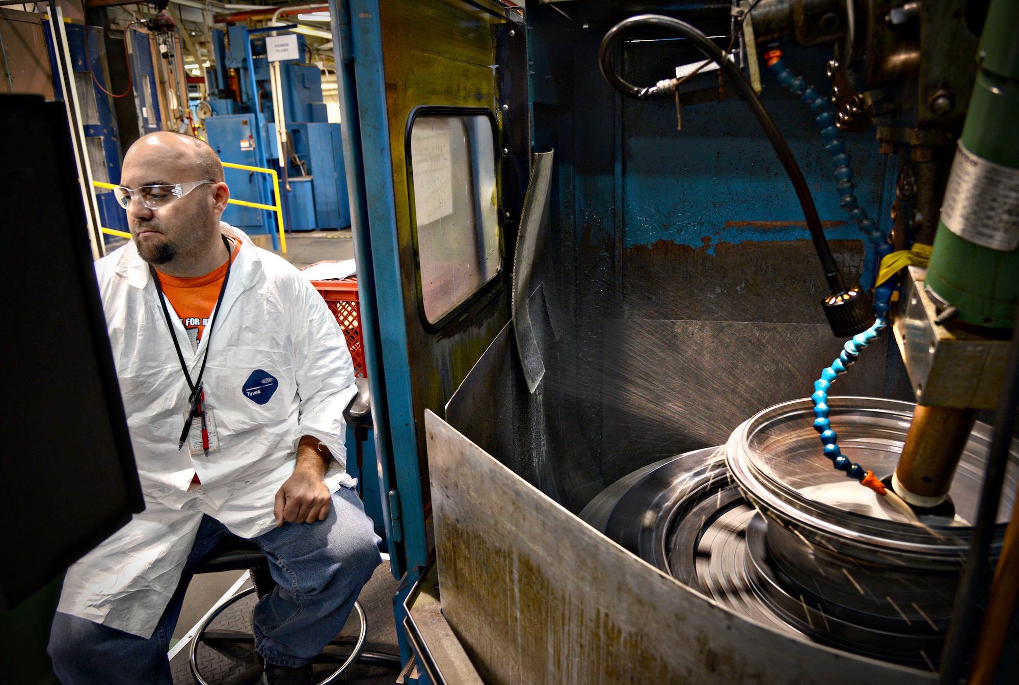 Josh Scroggins operates the spark erosion machine on a gear nozzle for an F108 engine. (Air Force photo by Kelly White/Released)