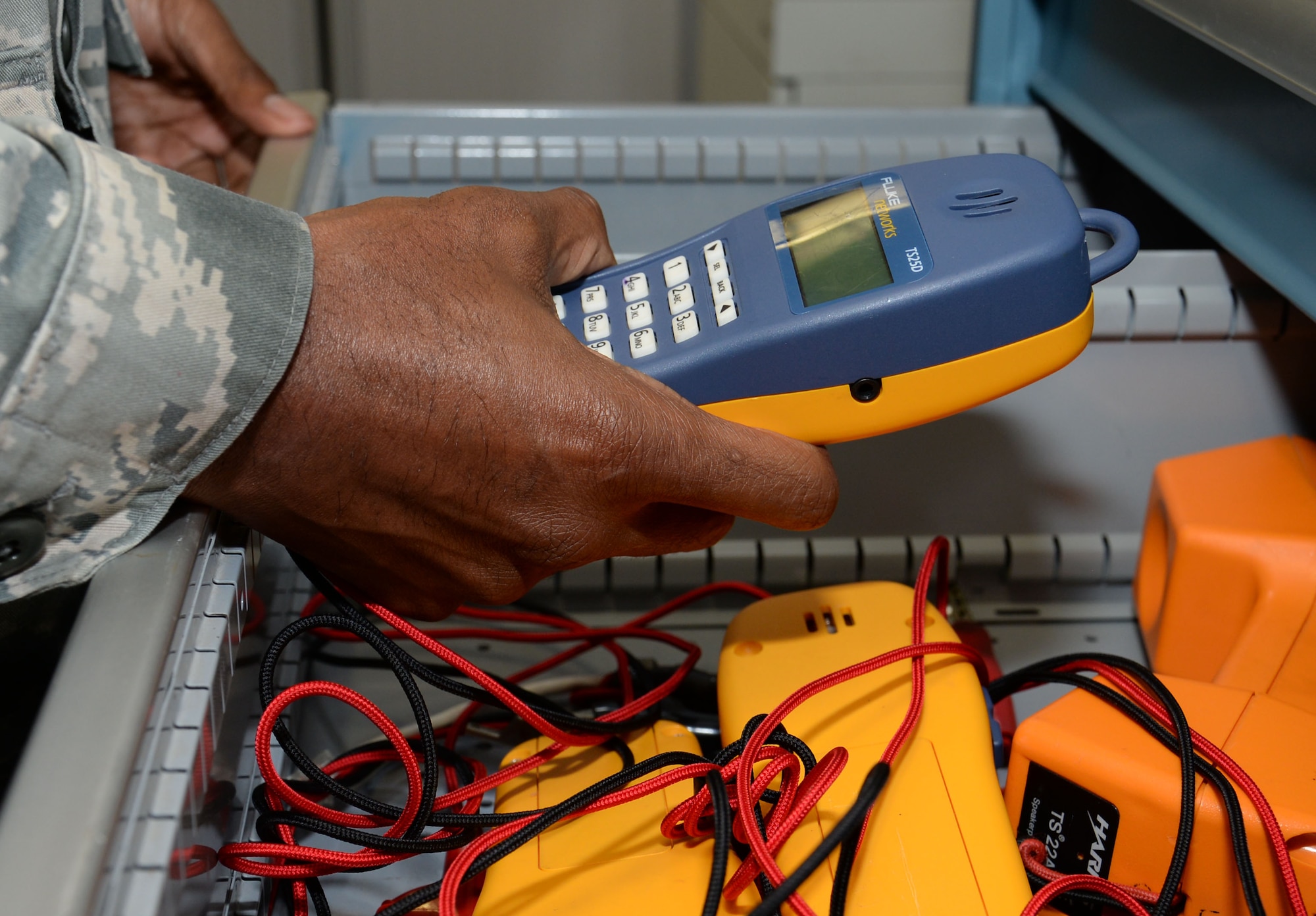 U.S. Air Force Staff Sgt. Christerfer James, 100th Communication Squadron Cyber Transport supervisor, takes an analog butt set from the cabinet Sept. 4, 2015, on RAF Mildenhall, England. James was using the butt set to test analog line across the base. (U.S. Air Force photo by Gina Randall/Released)