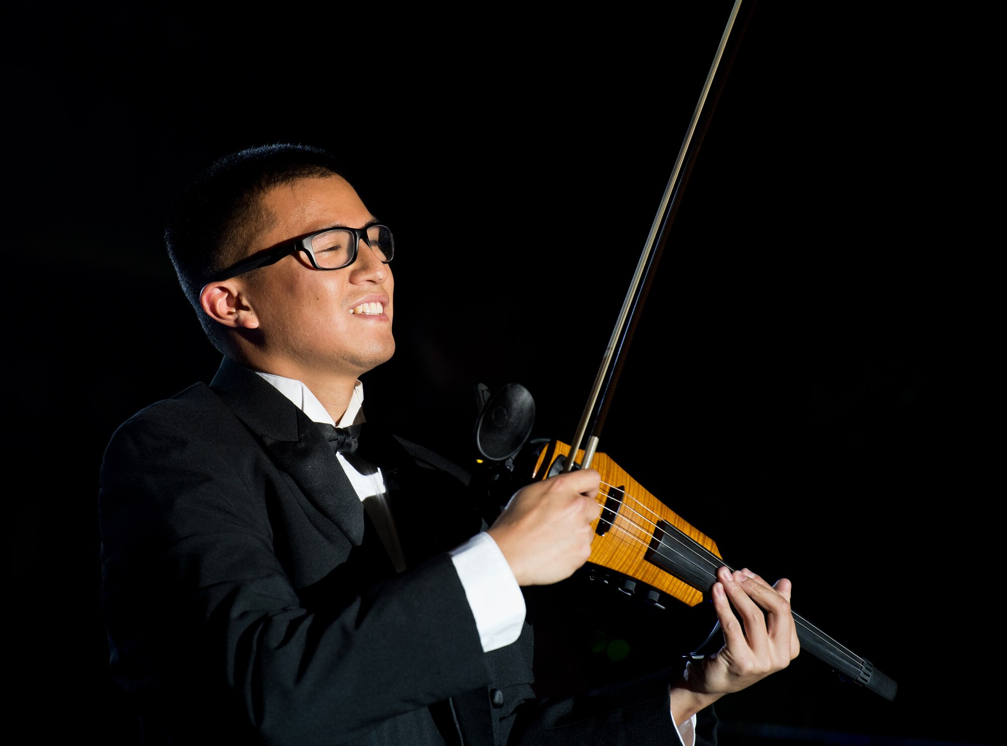 First Lt. Oliver Chang, Space and Missile Systems Center developmental engineer, plays a violin during a Tops in Blue concert Sept. 27, 2015, on Ramstein Air Base, Germany. During each annual tour, Tops in Blue entertains more than 250,000 military personnel and their families, presenting an average of 120 performances at 100 locations worldwide. (U.S. Air Force photo/ Senior Airman Jonathan Stefanko)