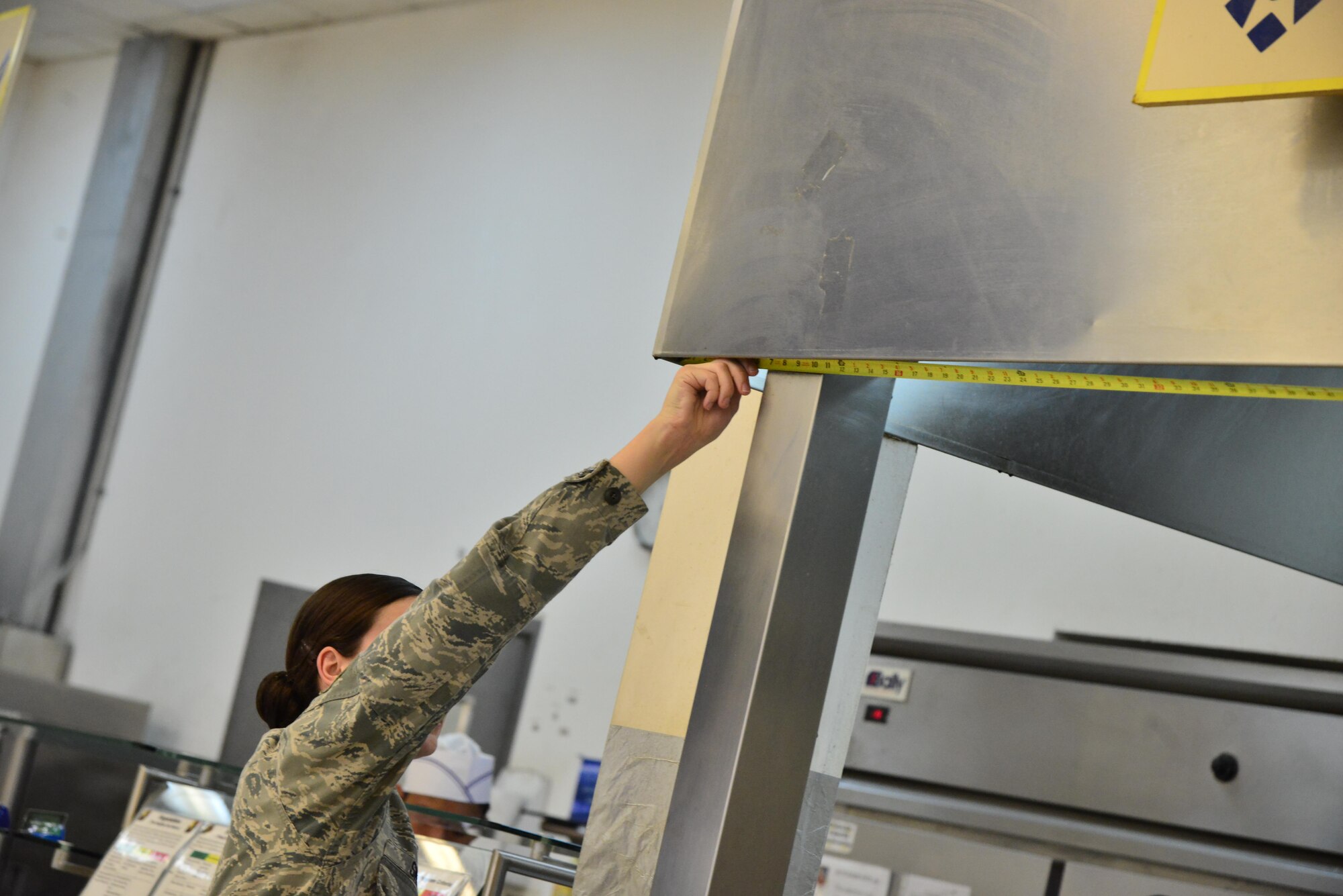 Senior Airman Leah Smith, 379th Expeditionary Medical Operations Support Squadron Bioenvironmental, helps measure the dimensions of a ventilation system inside a dining facility before conducting test for air flow rate September 30, 2015 at Al Udeid Air Base, Qatar. (U.S. Air Force photo/Staff Sgt. Alexandre Montes)