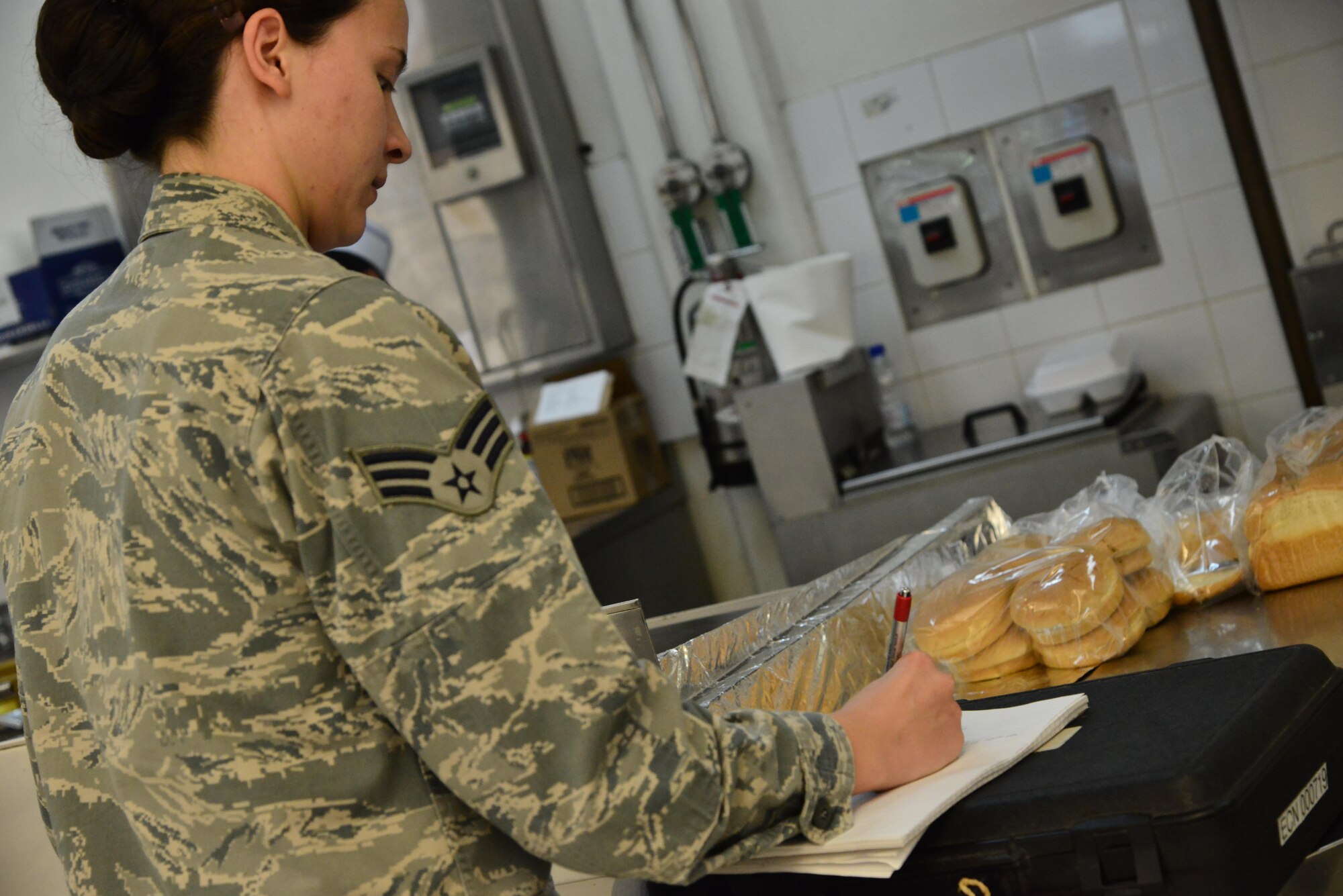 Senior Airman Leah Smith, 379th Expeditionary Medical Operations Support Squadron Bioenvironmental, writes down exact measurements of a ventilation system to compare them with Occupational Safety and Health Administration standards for cooking safety September 30, 2015 at Al Udeid Air Base, Qatar. (U.S. Air Force photo/Staff Sgt. Alexandre Montes)