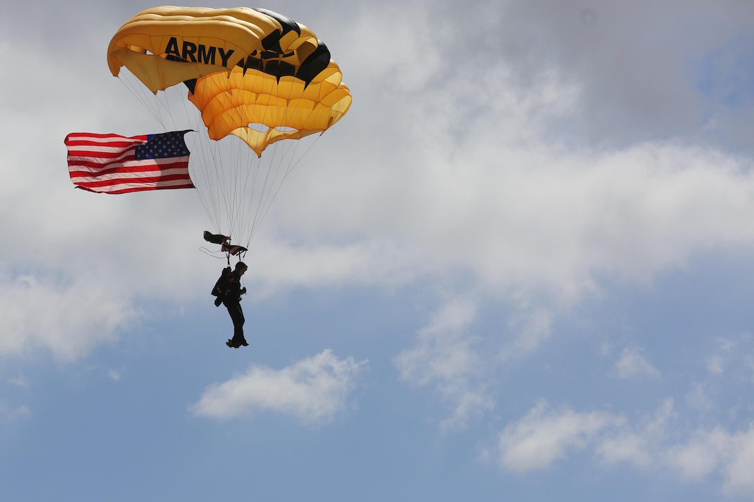 A parachutist with the U.S. Army’s Golden Knights landed on the flight line trailing the American flag as the 3rd MAW band played the national anthem during the opening ceremony of the 2015 MCAS Miramar Air Show aboard Marine Corps Air Station Miramar, Calif., Oct. 2. The air show began with an opening ceremony followed by the Marine Air Ground Task Force demonstration. (U.S. Marine Corps photo by Sgt. Melissa Wenger/Released)