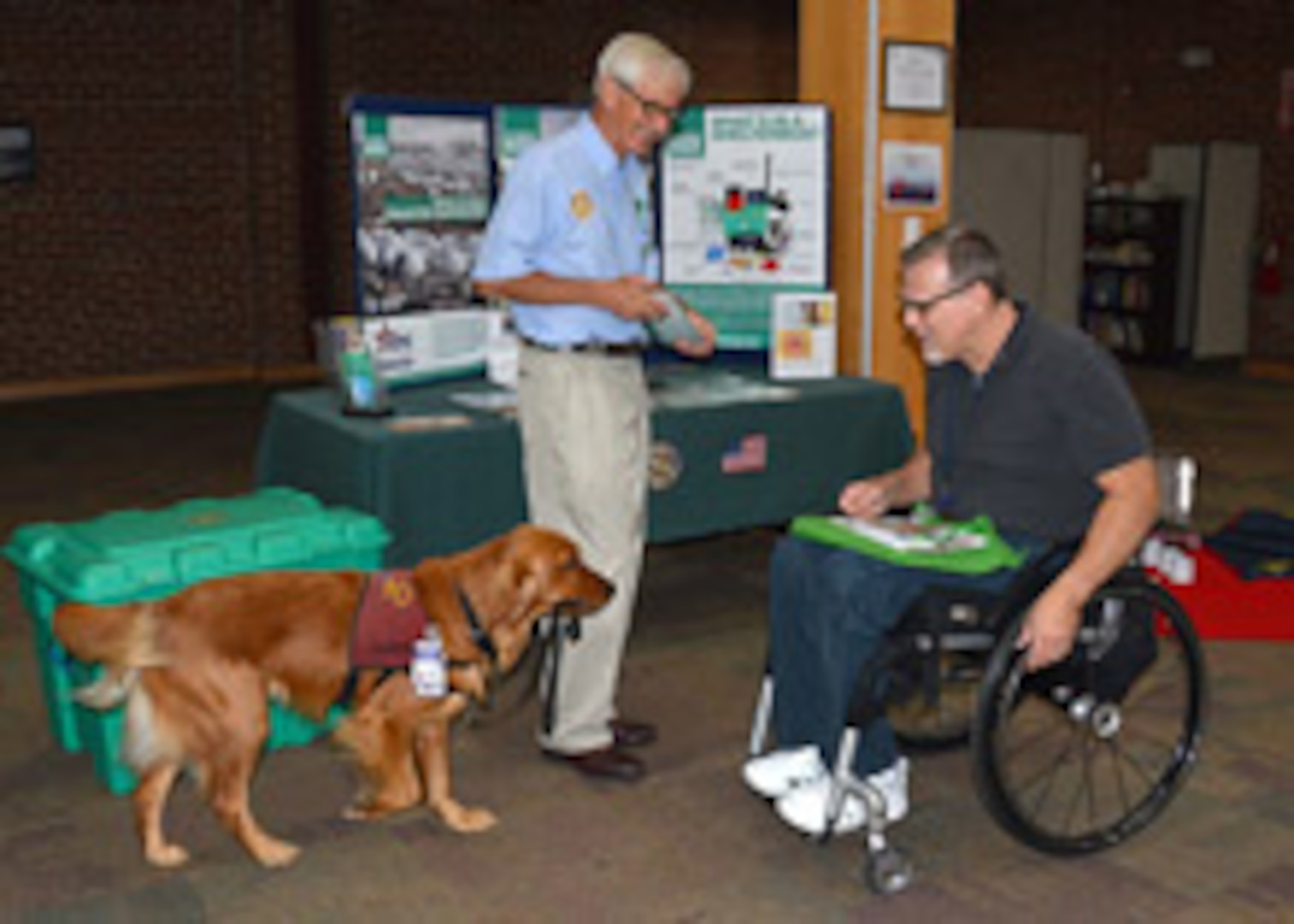 A ‘Pets for Vets’ employee, Jackson (the Retreiver) decides to visit with Defense Logistics Agency Aviation’s Marc Miller, a supply systems analyst for Business Process Support Directorate, as Miller visits at the Shelter in a Box table during the Combined Federal Campaign kick-off event held Sept. 23, 2015 in the Frank B. Lotts Conference Center, Richmond, Virginia. 