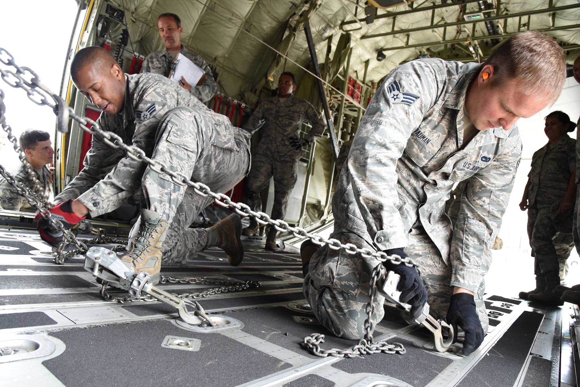 Senior Airmen Jiminez Edwards (left) and Eric Bauman, 403rd Aerial Port Squadron aircraft transportation journeymen, secure a Humvee to the floor of the cargo compartment of a C-130J during the “chains and devices tie down” event of the “Port Dawg” Challenge Oct. 3, 2015, at Keesler Air Force Base, Mississippi. The competition is designed to develop healthy competitiveness and esprit de corps while working on building a more proficient aerial port squadron. (U.S. Air Force photo/Tech. Sgt. Ryan Labadens)