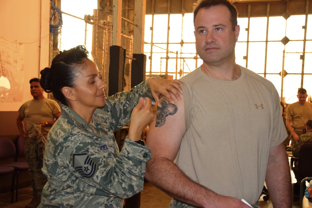 Master Sgt. Jeanett Vielman, a 433rd Aeromedical Staging Squadron lead medical technician, delivers the influenza vaccination to Tech. Sgt. Randy Warner, a 433rd Force Support Squadron Communication Flight training manager, on Oct. 03, 2015 at Joint Base San Antonio-Lackland, Texas. The 433rd Medical Group medics also passed out complimentary hand sanitizer and reminded wing members about hygiene as the nation enters the flu season.  (U.S. Air Force Photo/Tech. Sgt. Carlos J. Trevino/Released)
