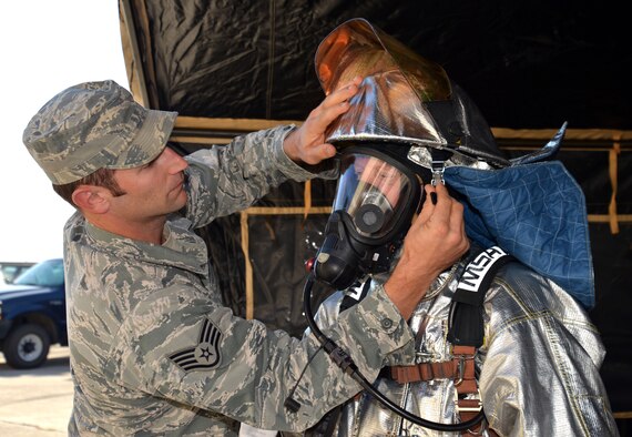 Staff Sgt. Moss of the 433rd Civil Engineer Squadron Fire Department, assists Dr. Glen Gross, University of Texas Health Science Center at San Antonio Gastroenterology Division chief, in putting on a fire suit helmet Oct. 3, 2015 at Joint Base San Antonio-Lackland. The demonstration was part of a 433rd Airlift Wing Honorary Commander program tour of the 433rd Mission Support Group. (U.S. Air Force photo/Tech. Sgt. Lindsey Maurice)
