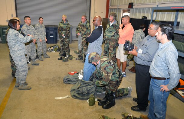 Tech. Sgt. Rosemarie Camacho (left) of the 433rd Logistics Readiness Squadron explain to 433rd Airlift Wing Honorary Commanders how to properly don chemical gear during the civic leaders’ tour of the 433rd Mission Support Group. The Honorary Commanders program provides a unique opportunity for San Antonio area community leaders to shadow the 433rd Airlift Wing, Group and commanders. (U.S. Air Force photo/Tech. Sgt. Lindsey Maurice)