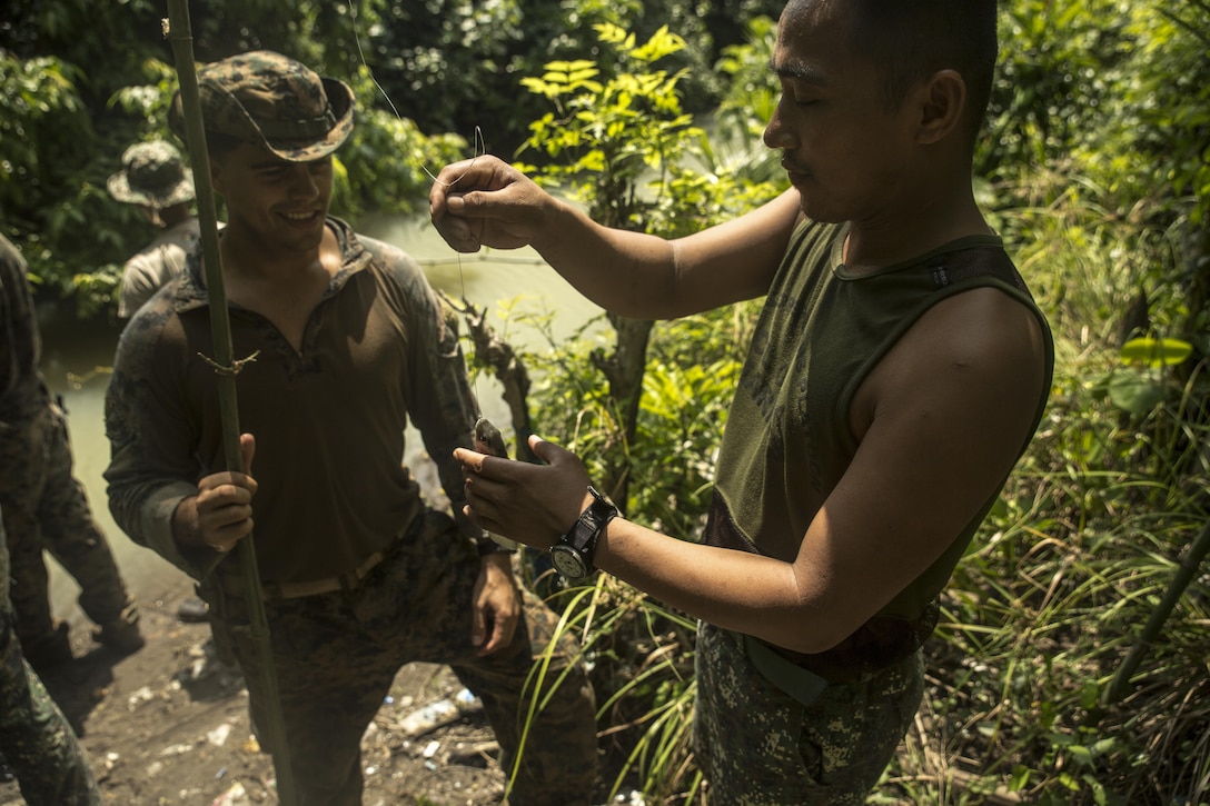 Philippine Marine Corps Cpl. Elmer Addatu, right, grabs a fish of the line of U.S. Marine Corps Cpl. Lucas Fernandez’s improvised fishing pole during jungle survival training at Ternate, Philippines, Sept. 30, as part of Amphibious Landing Exercise 2015. The Marines learned basic jungle survival skills, such as building a fire, finding sources of fresh water and catching food. PHIBLEX 15 is an annual, bilateral training exercise conducted by U.S. Marine and Navy Forces with the Armed Forces of the Philippines in order to strengthen our interoperability and working relationships across the range of military operations — from disaster relief to complex expeditionary operations. Addatu is a reconnaissance man with 64th Force Recon Company, Marine Special Operations Group. Fernandez from Greenwich, Connecticut, is a reconnaissance man with 3rd Recon Battalion, 3rd Marine Division, III Marine Expeditionary Force.