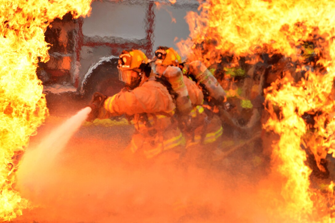 Air Force firefighters rush into extreme-heat temperatures to extinguish a fire during training in Garden City, Ga., Oct. 3, 2015. The firefighters are assigned to the Georgia National Guard's 165th Airlift Wing Fire Emergency Services Flight. Georgia National Guard photo by Air Force Staff Sgt. Noel Velez