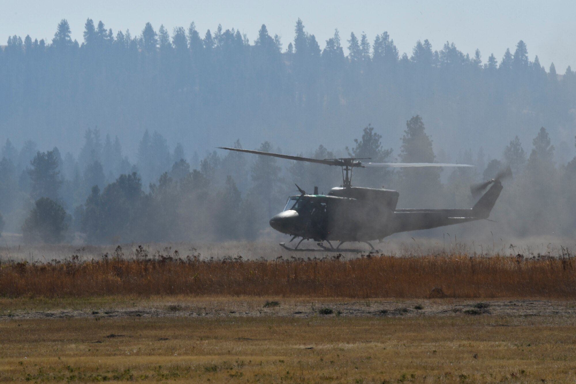 Maj. Robert Rennell, 36th Rescue Squadron assistant operations director, with copilot, Capt. Faith Sanderswalker, 36th RQS scheduling flight commander, and flight engineer, Staff Sgt. Dustin Sheffield, 36th RQS training flight NCO in charge, fly a UH-1N Iroquois helicopter during a parachute and rescue demonstration Sept. 29, 2015, at Fairchild Air Force Base, Wash. The demonstration was part of an Air Education and Training Command civic leader visit, which gave civic leaders an inside look at how Survival, Evasion, Resistance and Escape specialists are trained. (U.S. Air Force photo/Airman 1st Class Mackenzie Richardson)